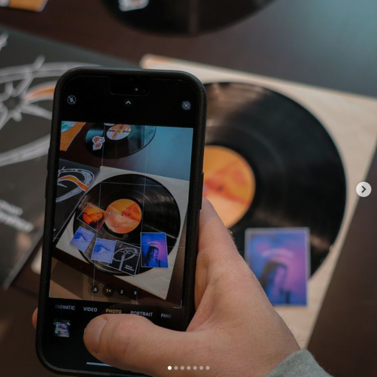Student with a cell phone taking a photograph of vinyl artwork.