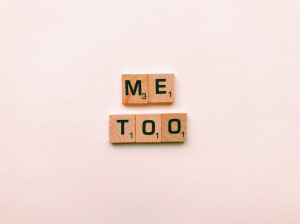 Scrabble tiles spelling "Me Too" on a pink background