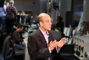 Man in newsroom talking to someone off screen
