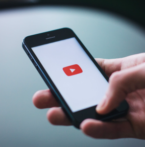 Hand holding cellphone displaying YouTube logo