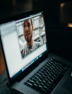 Laptop open with a man on screen video-chatting