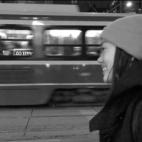 01: Girl smiling while waiting for streetcar. Medium Close Up & Eye Level Shot (Bordwell and Thompson, 189).