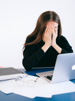 Can a computer read your emotions? Woman covering her face with her hands in front of a laptop