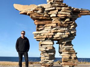 MMJC grad sharing Indigenous stories at CBC Colm Cobb Howes standing beside a rock structure