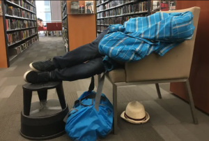 Do libraries need social workers on staff? Image of a man sleeping on a chair in the library
